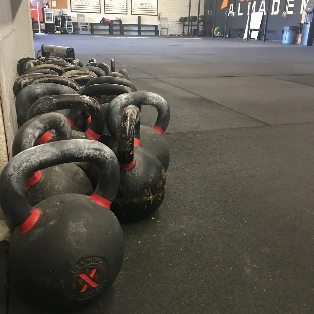Chalked kettlebells lined along the wall at CrossFit Almaden